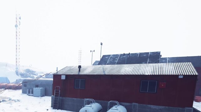 Buildings are visible in a snowy environment at a research station. Communication towers stand in the background. The scene shows a cold and remote area. Winter weather is present.