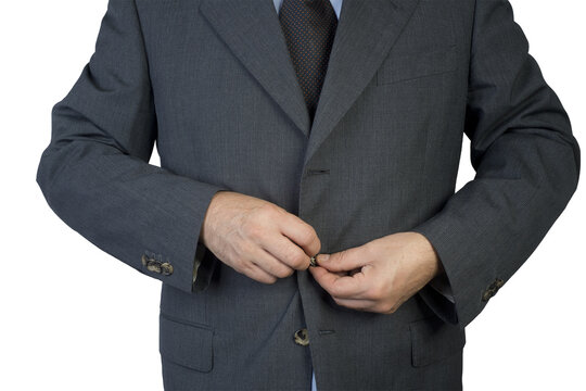 A person in a suit is buttoning their jacket.