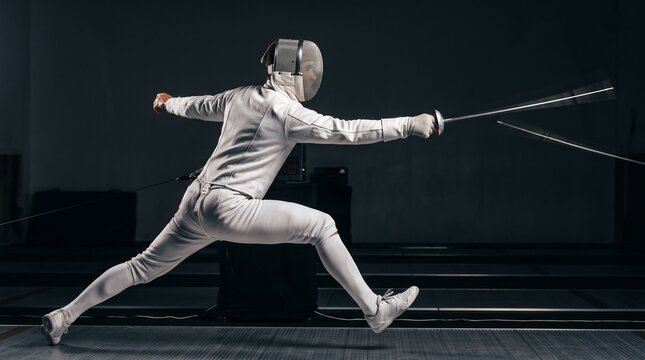 Action shot of fencer lunging with sword during fencing match in studio lighting background.