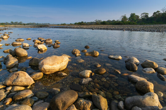 Murti river in the morning, riverbed in foreground with flowing water and stones. Scenic beauty of Dooars landscape, West Bengal, India. Dooars is popular tourist destination for natural landscapes.