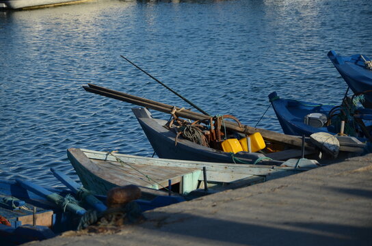 Small traditional wooden fishing boats moored at a concrete dock