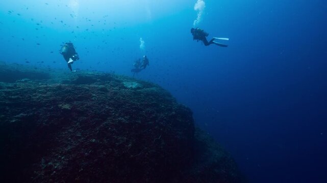 Group of SCUBA Divers drifting in strong current towards deep reef in Peleliu, Palau