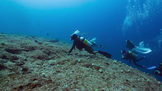 Underwater shot of SCUBA Divers in strong current being swept over a deep tropical reef in Peleliu, Palau	