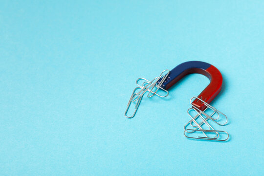 Paper clips that sticks to horseshoe magnet. Horseshoe Magnet Attracting Metal Paper Clips, Concept of Attraction, Connection, Influence, and Interdependence. Physical phenomena.