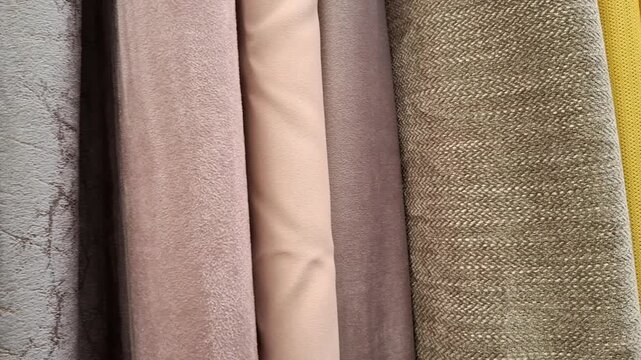 Close up view of various upholstery and curtain fabric samples hanging indoors, home interior textile decoration, furniture design materials.
