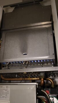 Vertical screen gas boiler ignition starts with blue flames as the burner fires up and begins heating the home marking the beginning of the colder weather heating seasons