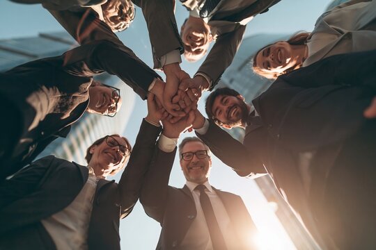 Diverse business team joining hands in a circle outdoors to symbolize unity and shared success