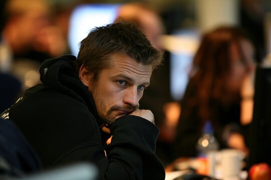 Exhausted bearded man resting chin on hand while sitting in office environment at night