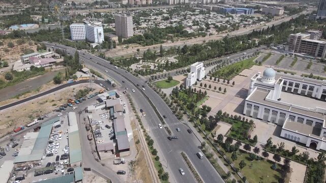 Cinematic aerial drone reveal over a major road in Dushanbe, Tajikistan, gradually revealing the city on a sunny summer day