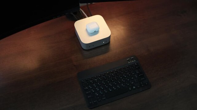 Modern mini computer with wireless earbuds and compact keyboard creates a clean home office desk setup for digital work productivity and everyday computing and media work