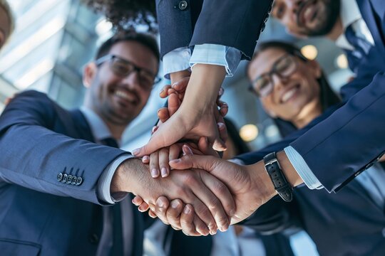 Diverse business team stacking hands together in a gesture of unity and collaboration in office