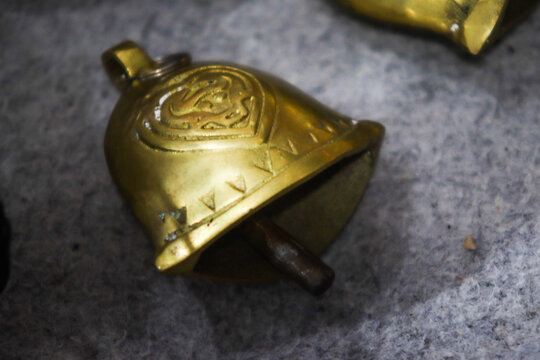 Ornate small brass bell on grey cloth surface macro close up
