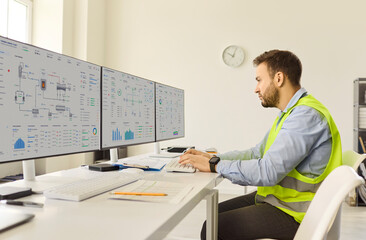 Engineer operator monitoring control systems with technology. He reviews data on multiple computer...