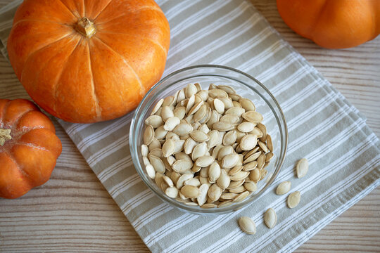 Bowl of raw pumpkin seeds and organic pumpkins