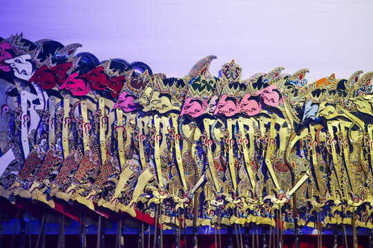 Ornate wayang kulit shadow puppet characters with vibrant pink and gold painted faces