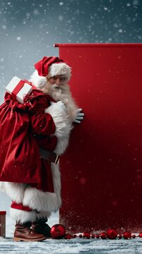 Santa stands beside a blank red panel. Snow gently falls around him in a quiet, magical setting. He holds a gift and smiles warmly. Perfect for holiday campaigns or Christmas messaging