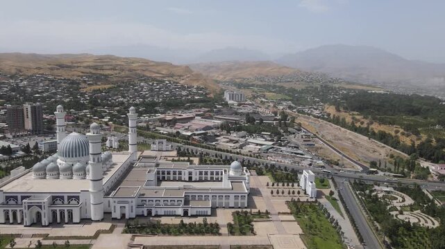 Aerial drone orbit around the Grand Mosque in Dushanbe, Tajikistan, with dramatic surrounding mountains on a sunny summer day