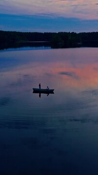 Vertical aerial view of father and son fishing in boat on Matildanjarvi lake Finland sunset