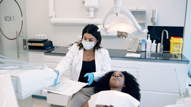 Dentistry professional preparing sterilised instruments for a patient lying on a dental chair inside a modern clinic