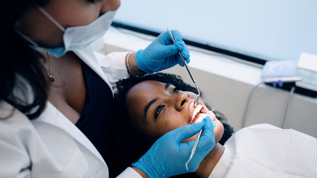 Dentist performing oral examination on patient in clinic, focusing on dental health, hygiene, and regular checkups