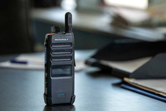 Motorola Solutions TLK 110 WAVE PTX broadband push-to-talk radio standing on a desk in an office environment.