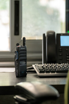 Motorola Solutions TLK 110 WAVE PTX handheld communication radio on an office desk beside computer and telephone equipment.