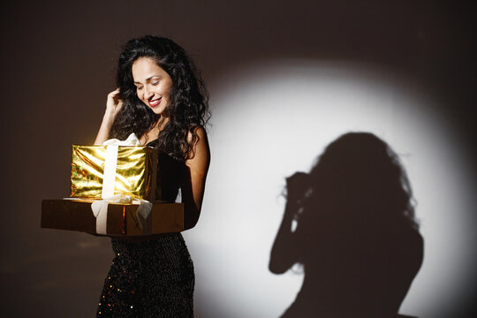Portrait of caucasian woman holding a gifts under a projector's light