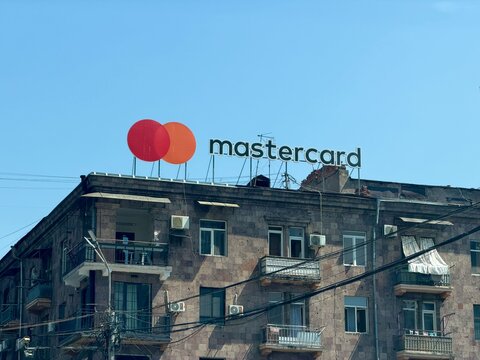 YEREVAN, ARMENIA - AUGUST 30, 2026: Mastercard logo sign on top of an old stone residential building under a clear blue sky.