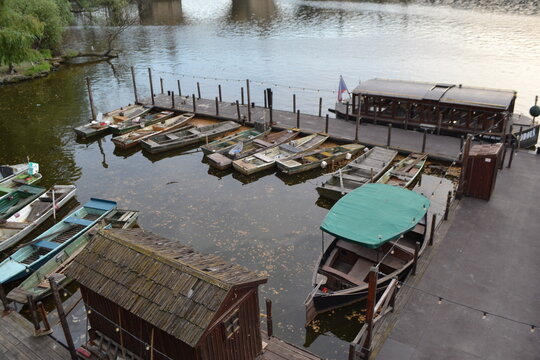 Riverside dock with multiple moored wooden boats and covered skiff for travel background and scenic landscape banner
