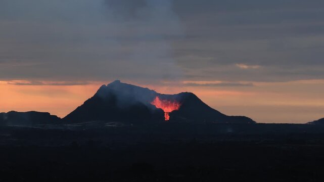 Volcanic eruption with glowing magma and smoke at sunset in Reykjavik, Iceland. Fagradalsfjall volcano erupting