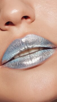 Close-up of lips adorned with chrome-like silver metallic lipstick. The hyperreal texture and reflective shine create a futuristic, luxurious beauty editorial vibe.