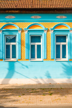 Vibrant blue and yellow historic house facade on a sunny street. Concept of traditional European architecture, urban color harmony, historic preservation, and decorative exterior design.