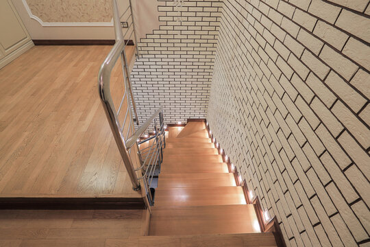 Wooden staircase step lights brick wall
