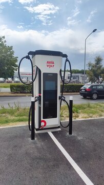 Royan, France - August 10, 2026: New Aquitaine, Charente-Maritime, Centre commercial. Electric vehicle charging station AVIA Volt with dual connectors in parking lot under cloudy sky