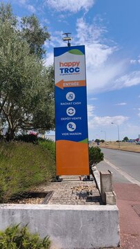 Royan, France - August 10, 2026: New Aquitaine, Charente-Maritime, Centre commercial. Happy Troc sign displaying services including cash purchase, consignment, and house clearance near commercial area