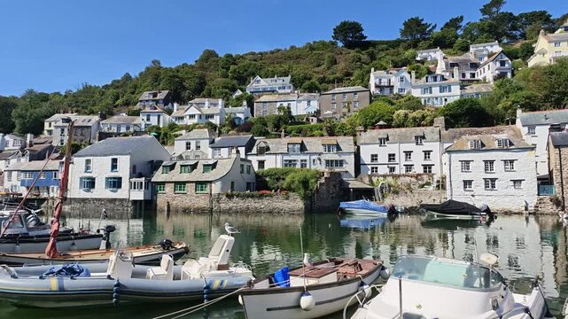 Polperro Cornwall Englnd UK. 13.08.2026. Charming coastal village of Polperro featuring traditional architecture and numerous boats peacefully moored in a calm harbour on a sunny day