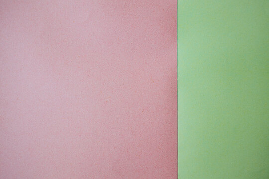 Pink and green textured paper sheets arranged side by side, showcasing a smooth surface with subtle variations in color and texture for creative projects