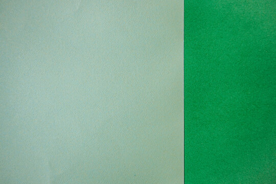 Two sheets of textured paper, one light blue and one vibrant green, placed side by side on a flat surface, showcasing distinct colors and textures for design purposes