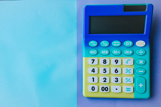 Colorful calculator with large buttons placed on a pastel blue background, featuring a blank area for notes or calculations beside it
