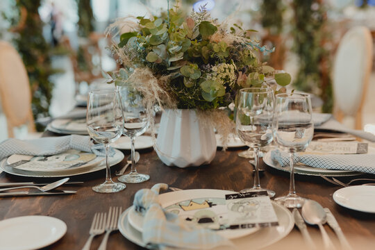 Elegant dining table with floral arrangements, glassware and place settings prepared for a formal event.