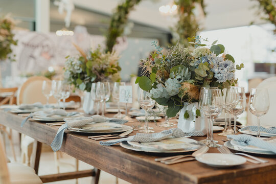 Elegant dining table decorated with flowers, glassware and place settings prepared for a formal celebration.