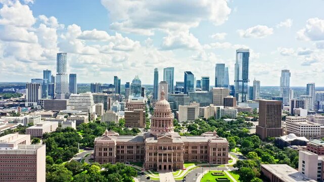 Fly over Texas State Capitol, the historic seat of government of Texas and one of the largest state capitol buildings in the United States, towards Austin skyline in the background