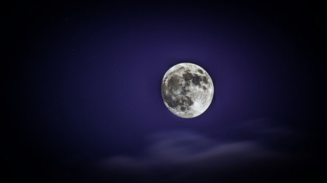 A luminous full moon, sharply defined with intricate crater details and a textured surface, dominates a dark, rich purple night sky, with soft, blurred clouds drifting below and a few tiny stars