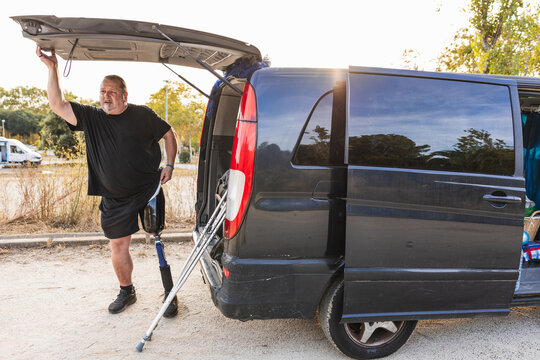 Man with prosthetic leg opening back of van