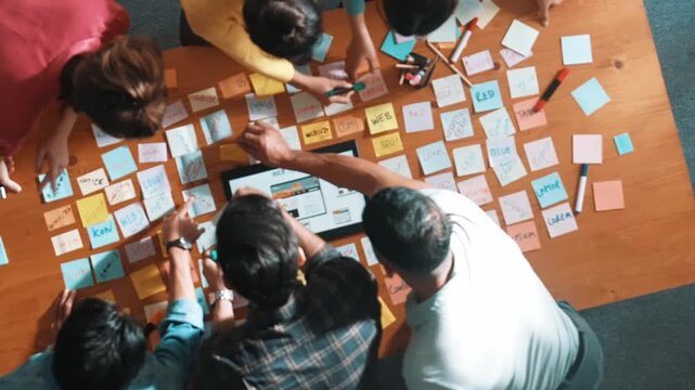 Aerial view of developer team discussing and showing digital program and writing by using Ux Ui design. Top down view of business people develop wireframe prototype for phone and computer. Symposium.