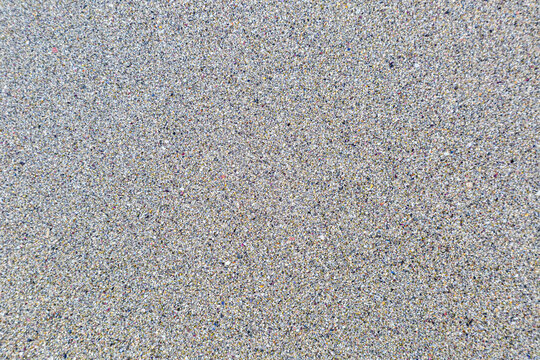 Abstrakte Nahaufnahme von feinem, mehrfarbigem Strandsand und kleinen Gesteinsk&ouml;rnern