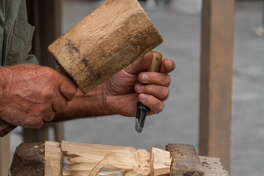 Craftsman carving wood with wooden mallet and gouge chisel