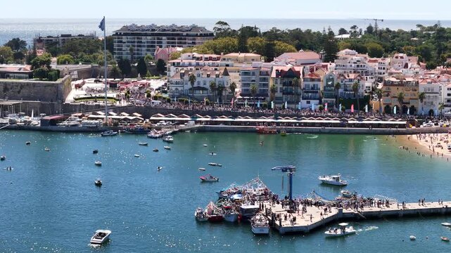 Cascais, Portugal - 30 August 2026: Aerial view of the coastal town of Cascais featuring a busy harbor with fishing boats, historic architecture, and clear blue water.