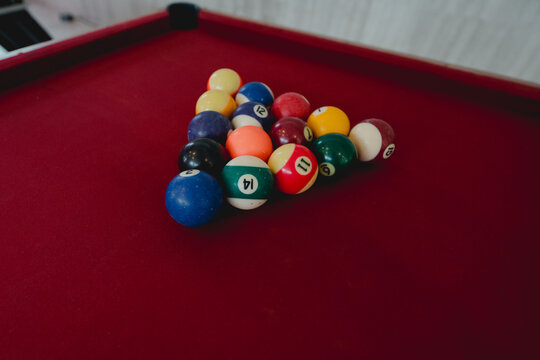Colorful billiard balls arranged on a red pool table with dramatic lighting and selective focus.
