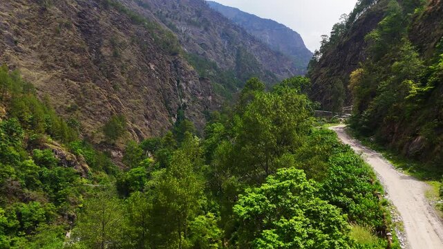 Langtang national park, Rasuwa, Nepal - 29 August 2026: Aerial view of the winding dirt road along the Trishuli river valley with lush green trees and steep mountain slopes.